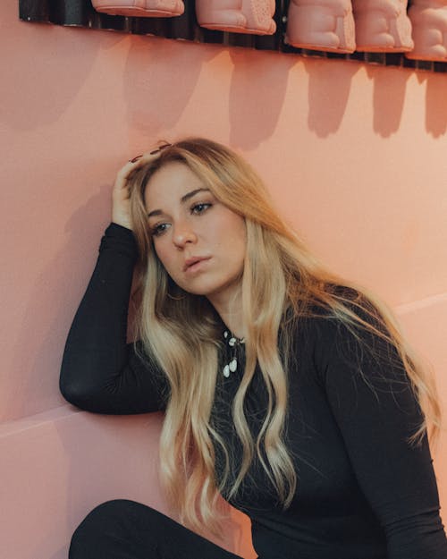 Young Woman Sitting by a Pink Wall 