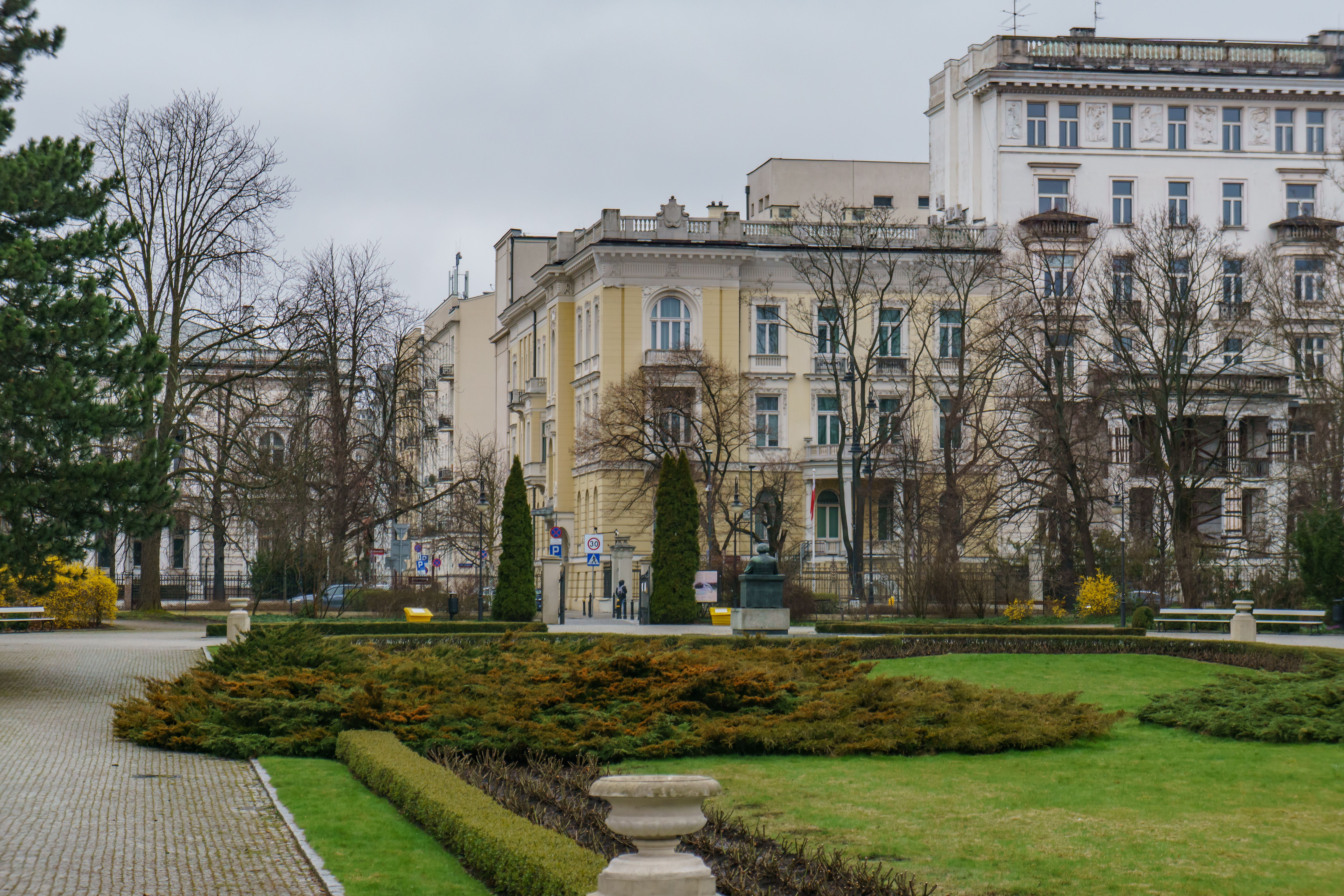 Classic European architecture with lush gardens in a Warsaw park, showcasing urban elegance.