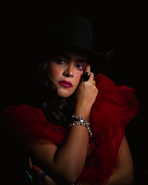 Studio Shot of a Woman Wearing a Black Hat and a Red Tulle Dress