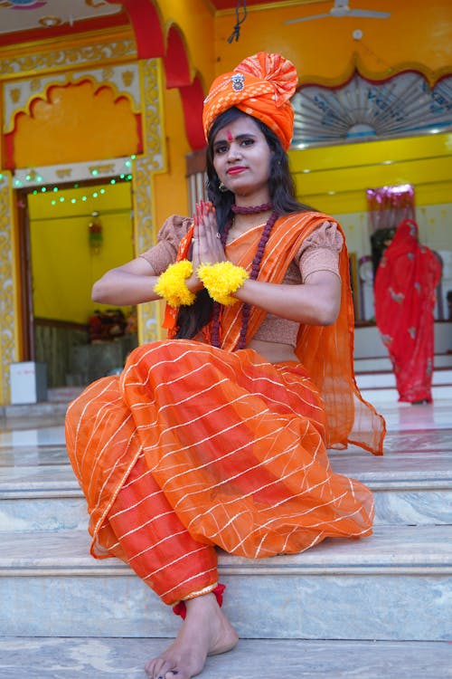 Woman in Traditional Clothing Sitting on Steps in front of a Temple 