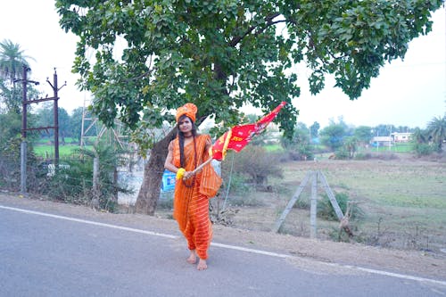Woman in Traditional Clothing Walking Outside with a Flag 