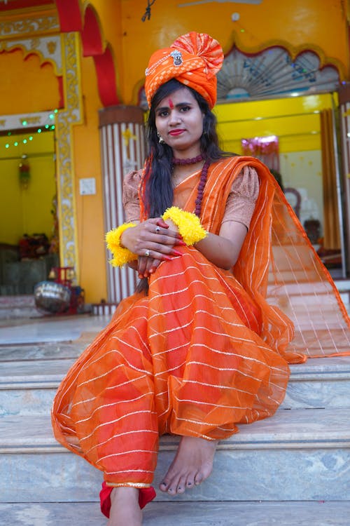 Woman in Traditional Clothing Sitting on Steps in front of a Temple 