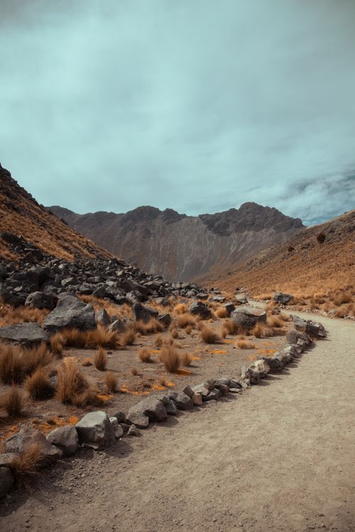 Free A serene mountain path winds through the arid landscape of Mexico, surrounded by rocks and hills. Stock Photo