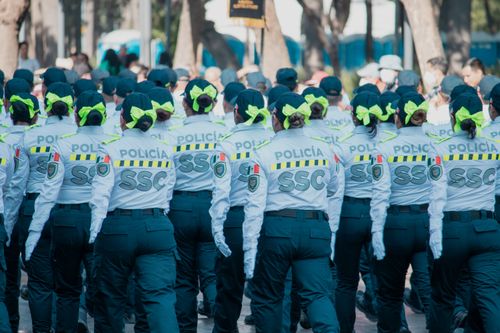 Free Women police officers in uniform marching in a parade with vibrant green bows in the city. Stock Photo