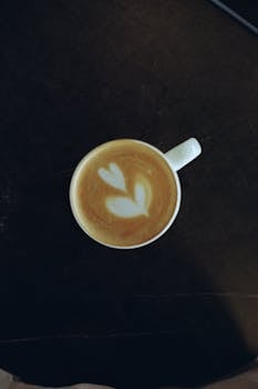 Top view of a cup of latte with heart-shaped foam art, perfect for coffee lovers.