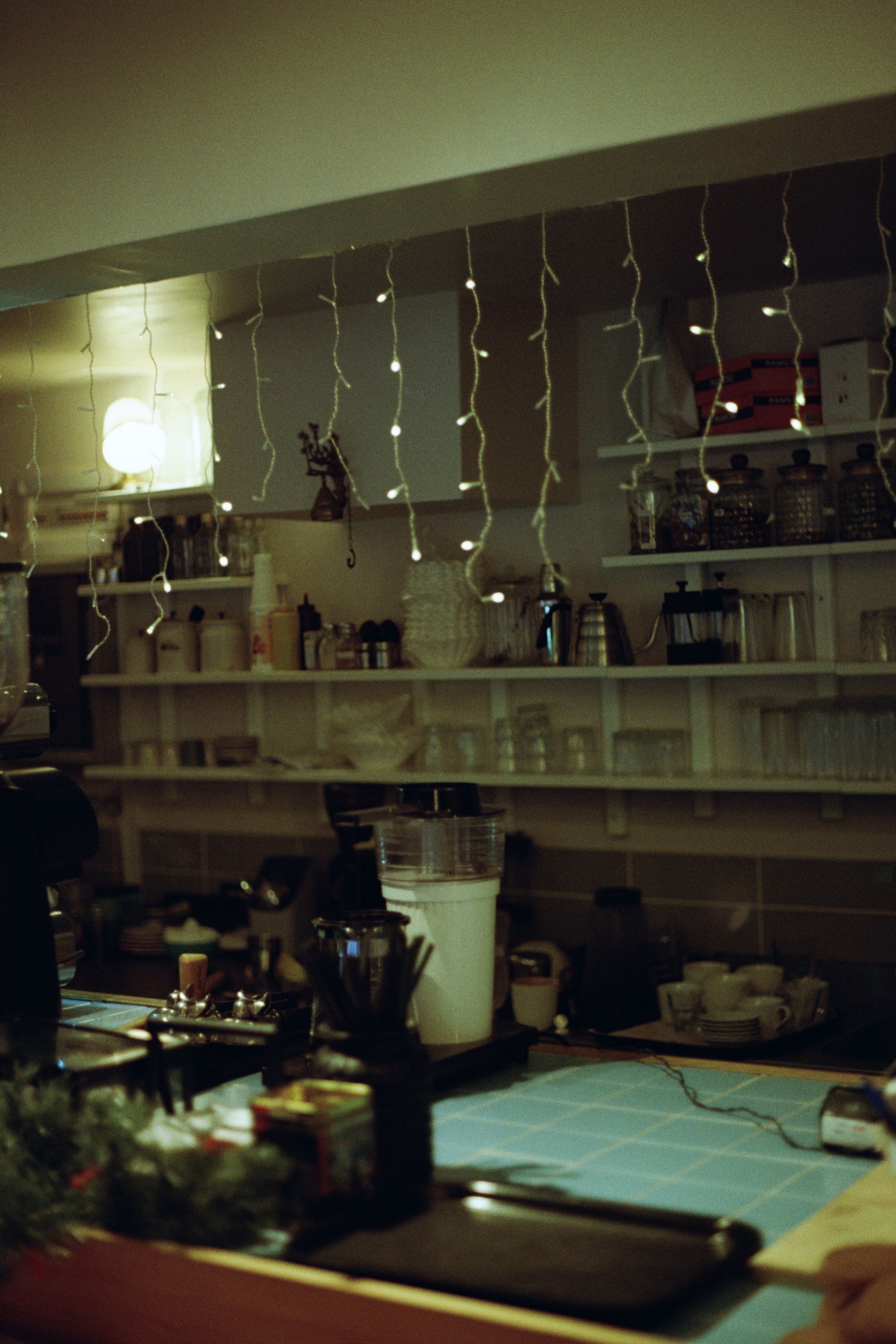 Warm fairy string lights draped behind a small boho coffee bar counter for ambient lighting