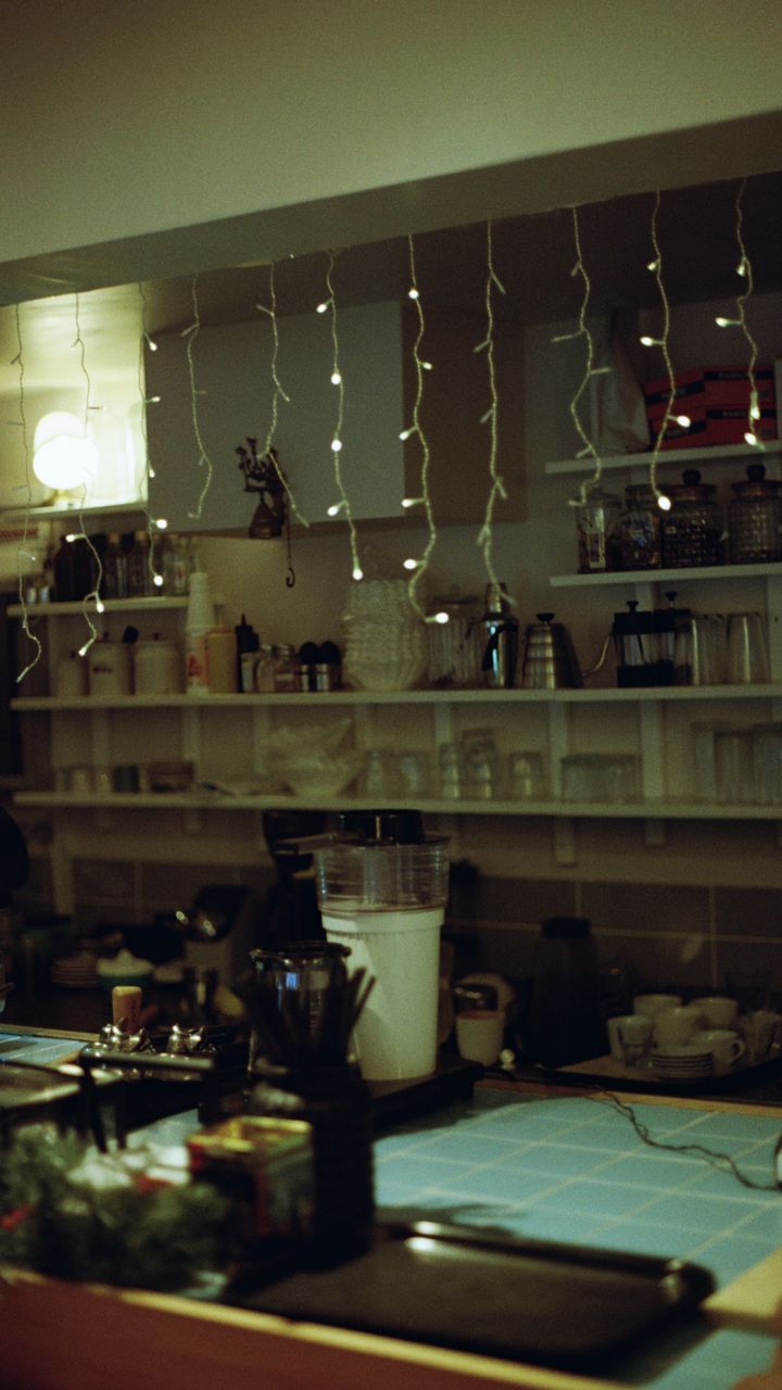Warm fairy string lights draped behind a small boho coffee bar counter for ambient lighting