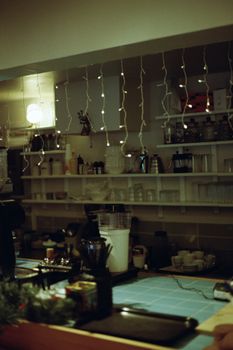 A cozy café setting featuring warm lights, counters, and shelves filled with kitchen items.
