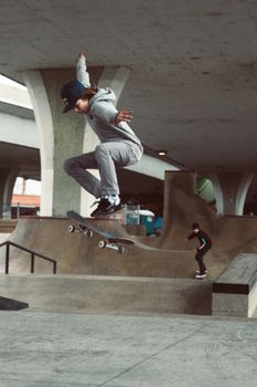 Skater performing a trick mid-air at an urban city skatepark beneath a concrete overpass.. skater, performing, trick