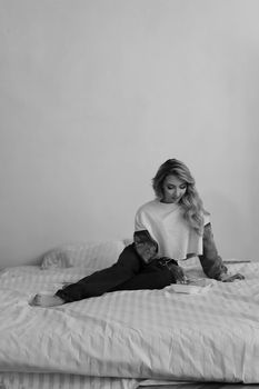 Elegant black and white photograph of a woman sitting on a bed, evoking a calm and introspective mood.