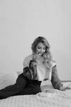 Black and white photo of a woman on a bed, showcasing fashion and elegance.