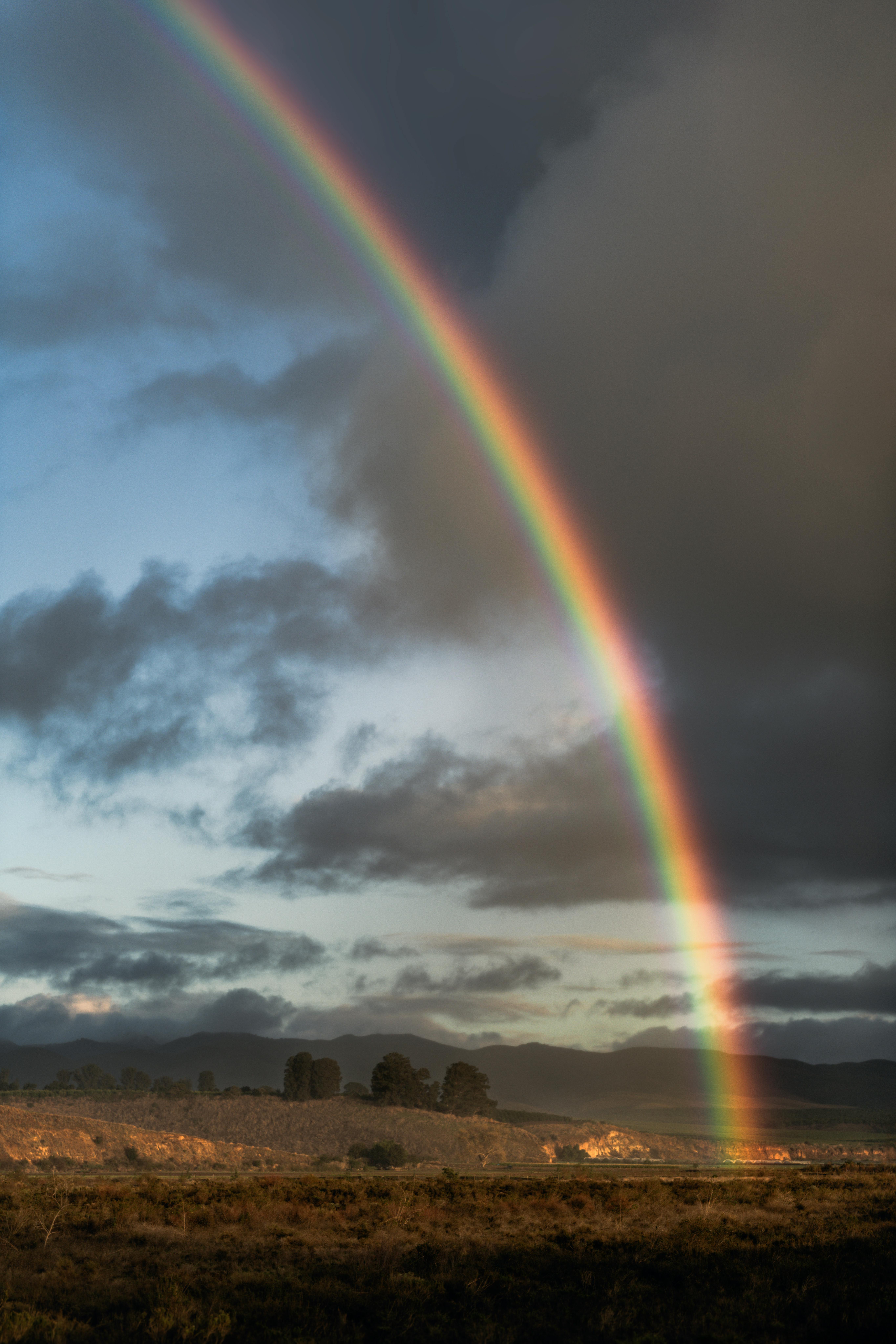 Stunning rainbow arcs over Santa Maria's rural landscape at golden hour.