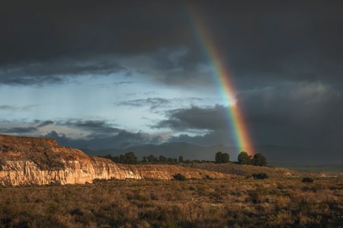 Free A stunning rainbow arcs over the rugged landscape near Santa Maria, California, under an overcast sky. Stock Photo