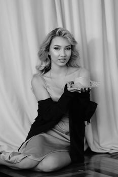 Elegant woman in evening dress holding a cake, black and white photography.