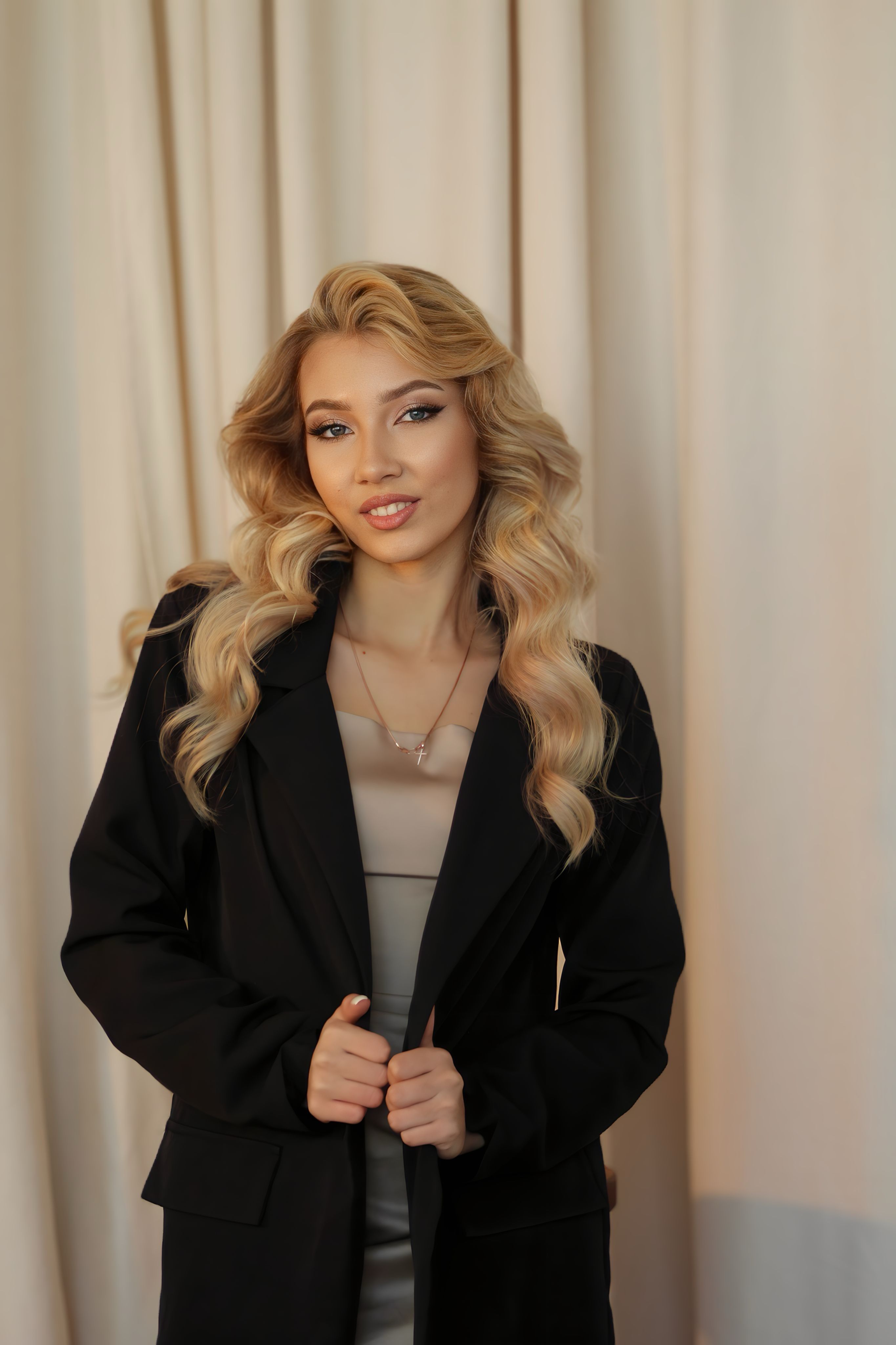 Portrait of a smiling blonde woman in a black suit jacket, exuding elegance and style.