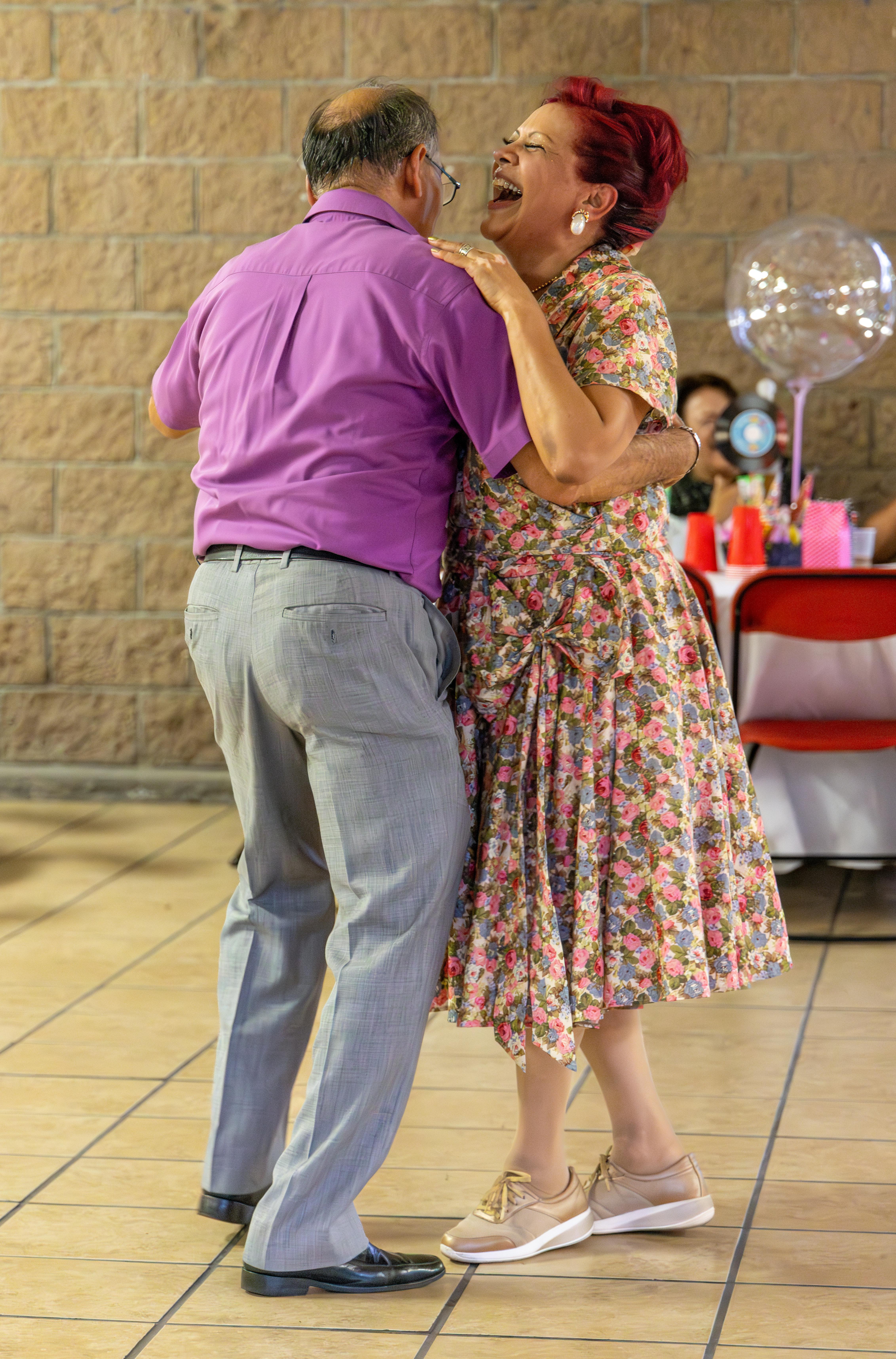 Elderly couple enjoying a lively dance together at a festive indoor party.
