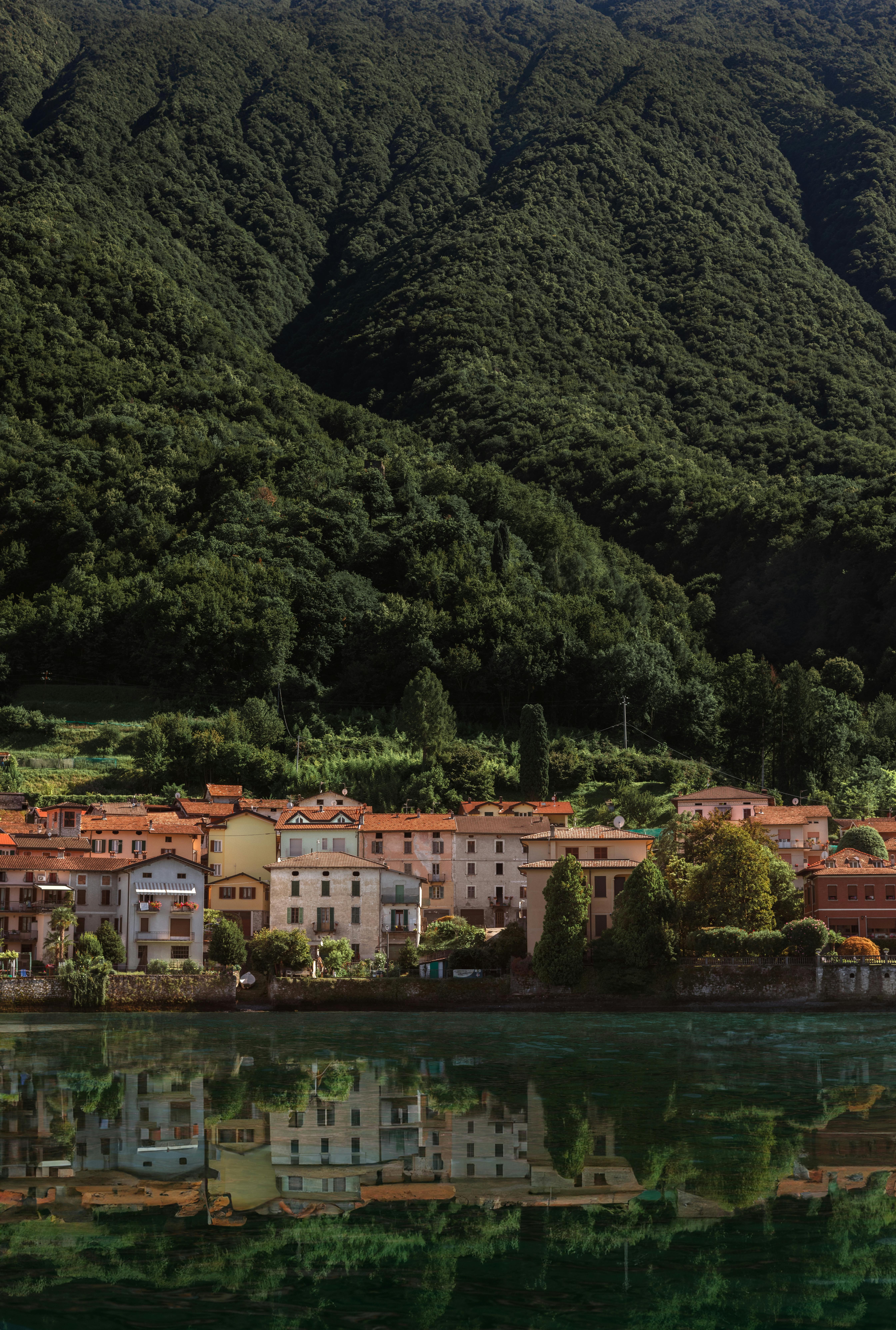 Picturesque view of Como town reflecting on a tranquil lake surrounded by lush mountains in Italy.