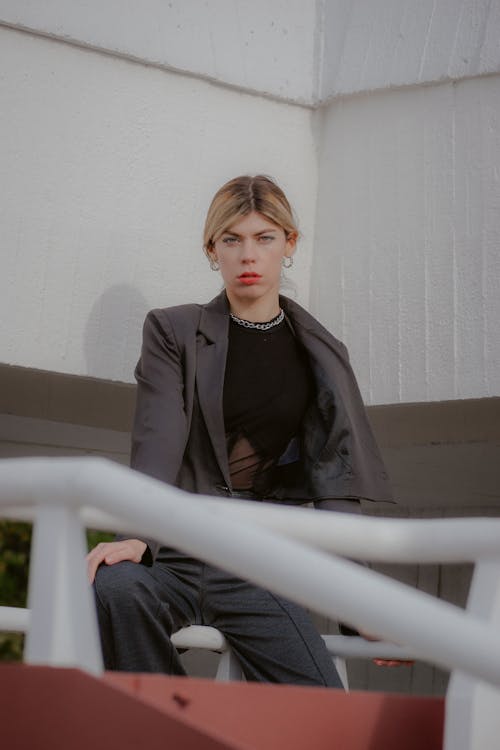 Blonde Woman in Gray Suit Sitting on Handrail