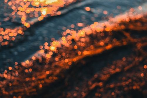 Free Abstract bokeh of ocean waves with warm sunset reflections, creating a dreamy atmosphere. Stock Photo