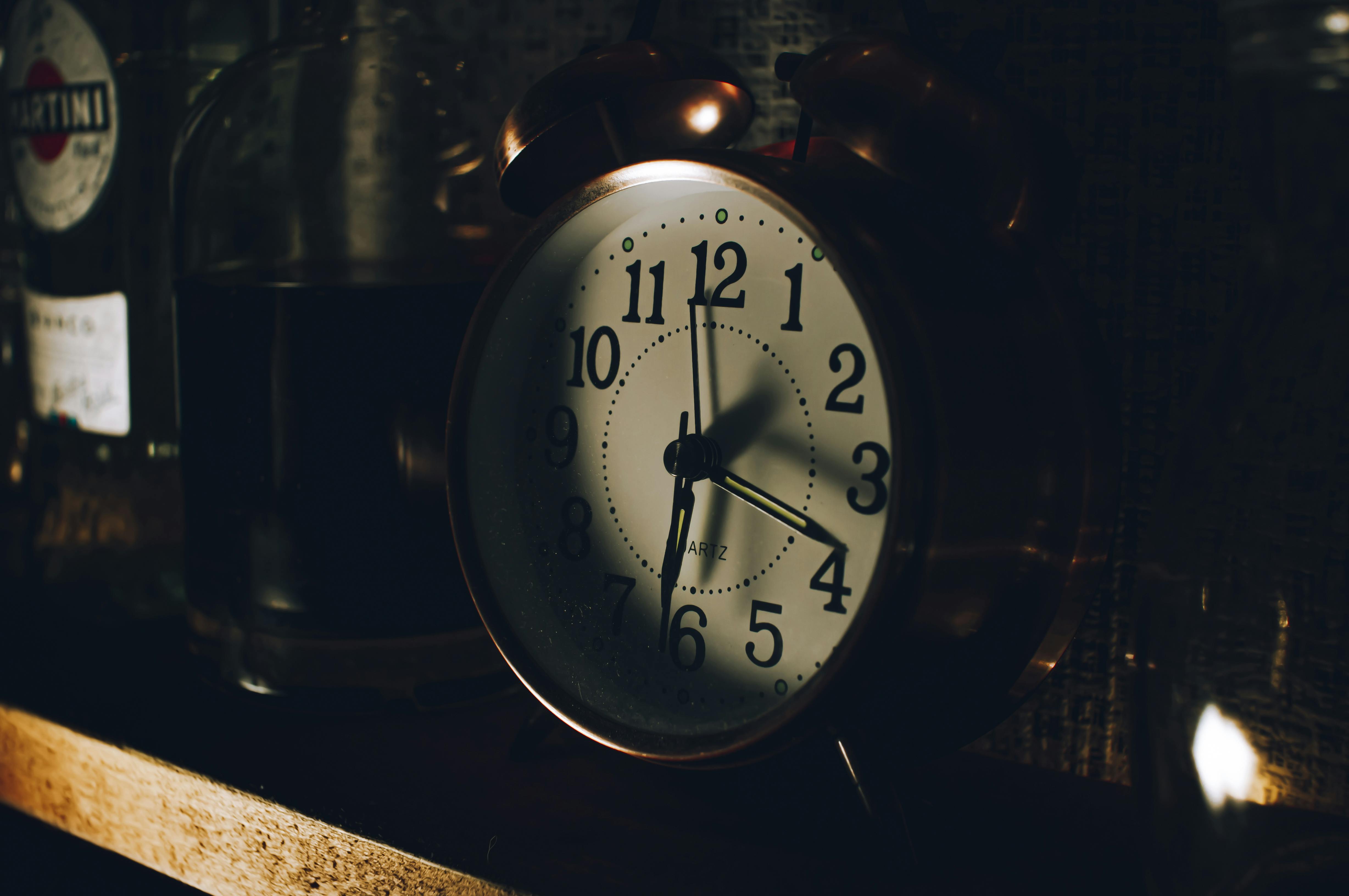 A clock sitting on a shelf next to bottles