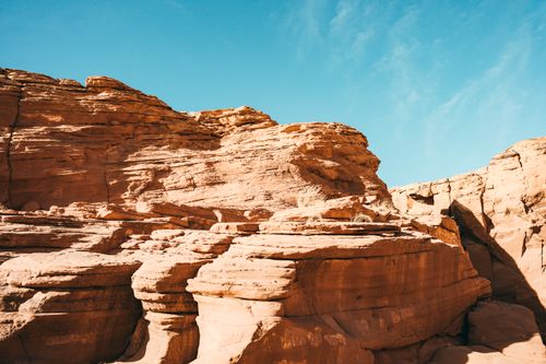 Free Explore sunlit sandstone formations against a clear blue sky in a vibrant desert landscape. Stock Photo