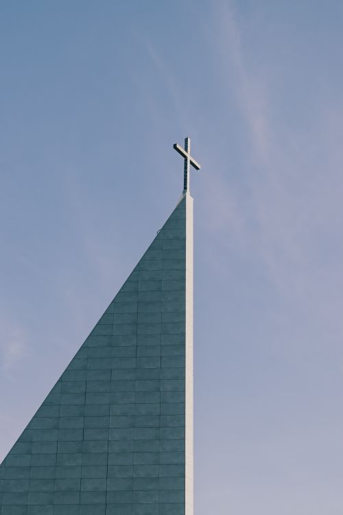 Free A modern church structure with a cross, captured against a clear blue sky. Stock Photo