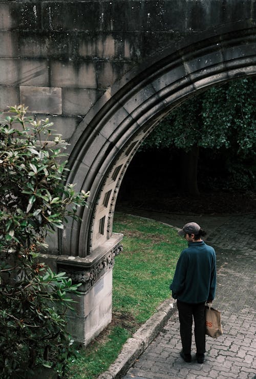 Man with Bag Standing under Arch at Park