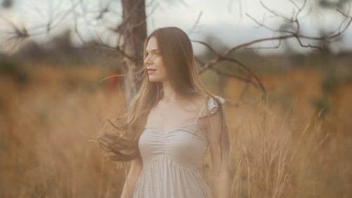 Free A serene portrait of a woman standing in a rural field, embracing nature. Stock Photo