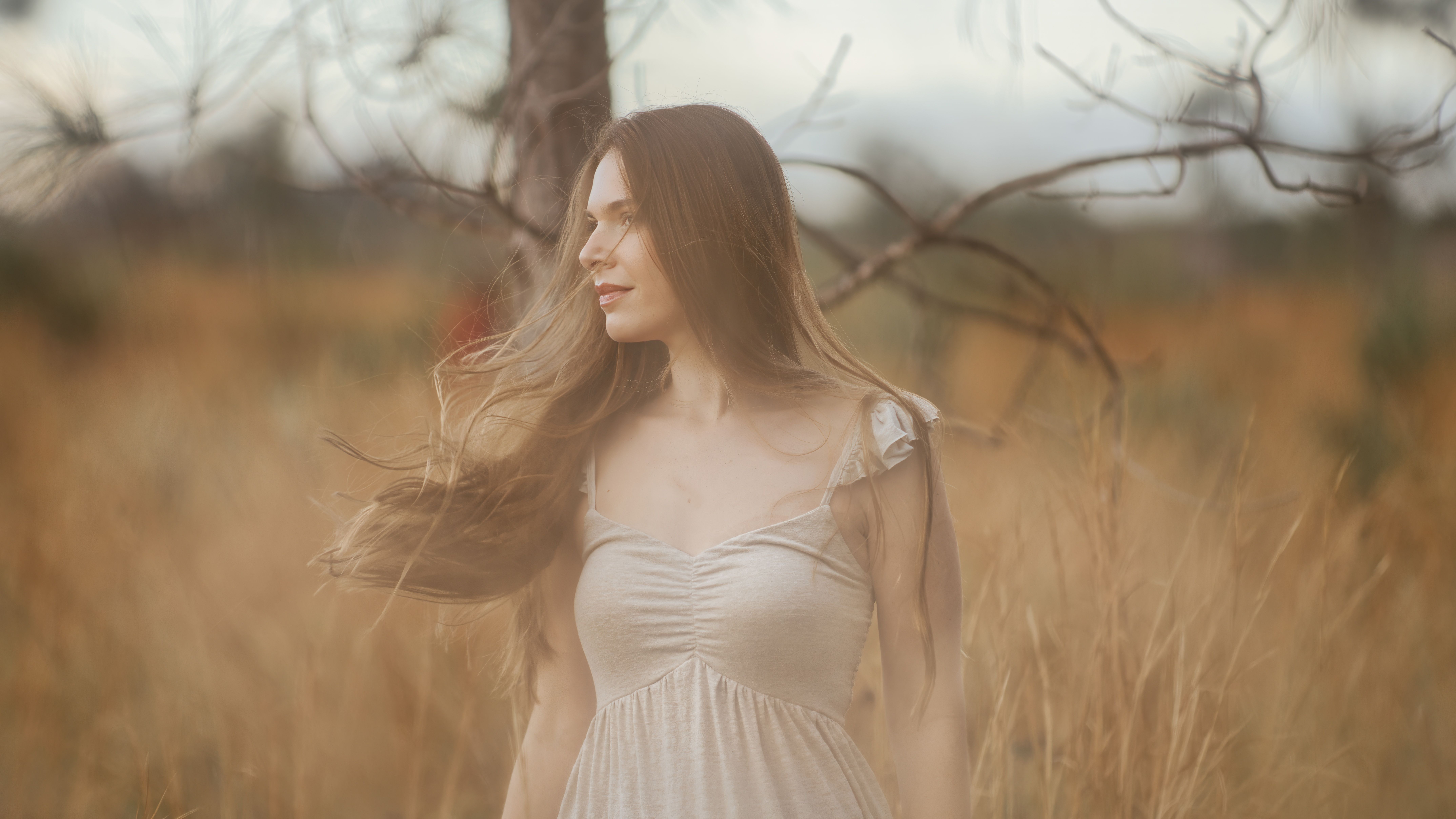 A woman in a white dress enjoys the calm of a rural field.