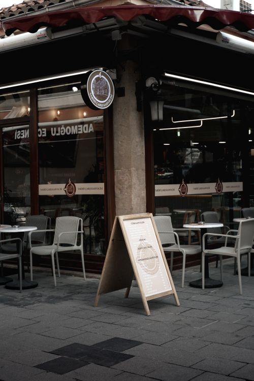 Free Charming urban café exterior with seating and a sidewalk sign in a quaint town corner. Stock Photo