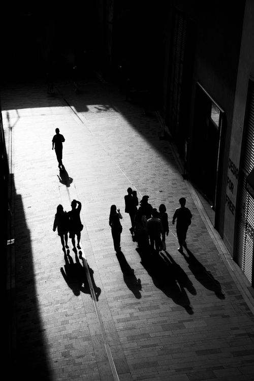 Free Dramatic urban scene with people casting long shadows on a city street. Stock Photo