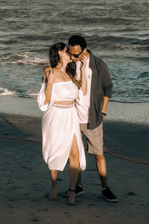 Free Woman in White Dress and Man Kissing on Beach Stock Photo