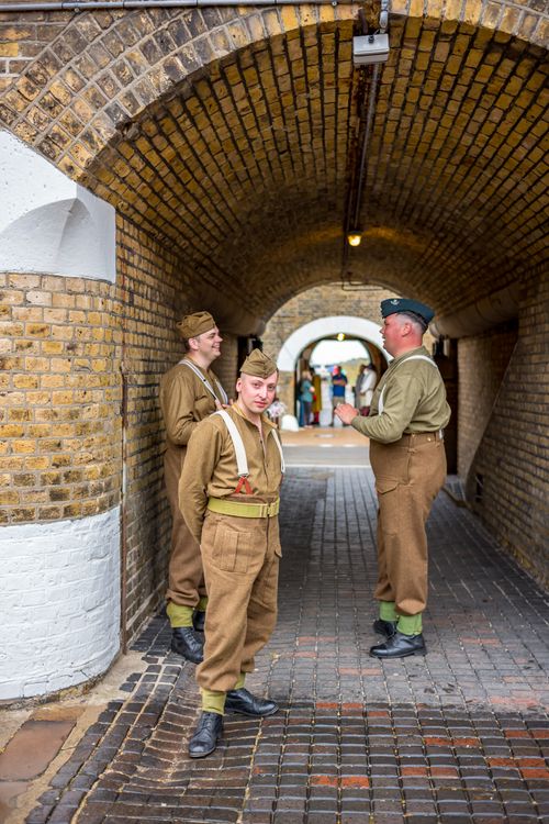 Free Men in vintage military uniforms reenact a historical scene in a brick tunnel. Stock Photo