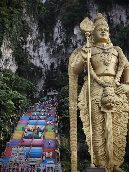 Free A statue of a large hindu god is standing in front of a large mountain Stock Photo