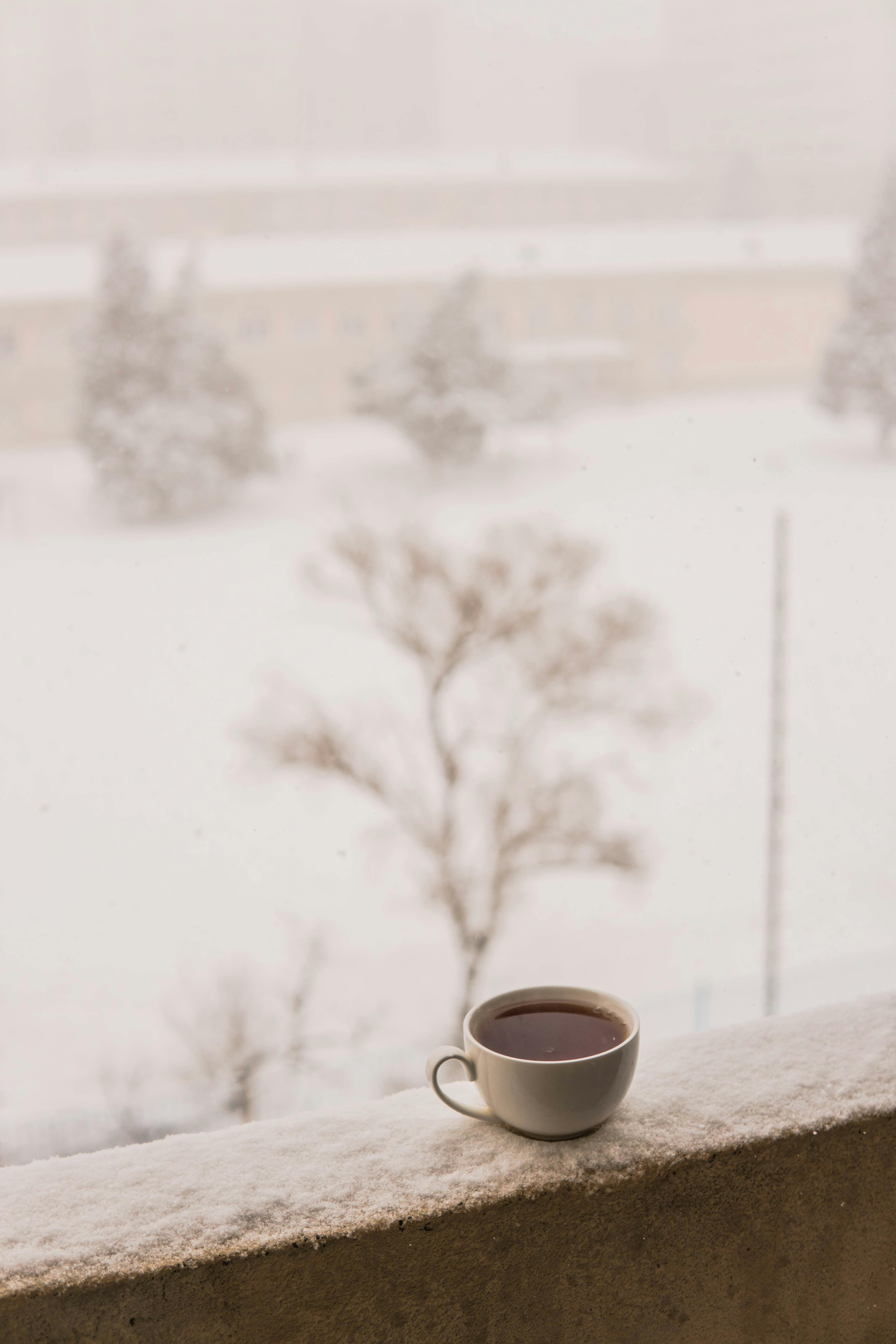 Warm cup on handrail overlooking a snowy landscape in Azerbaijan.