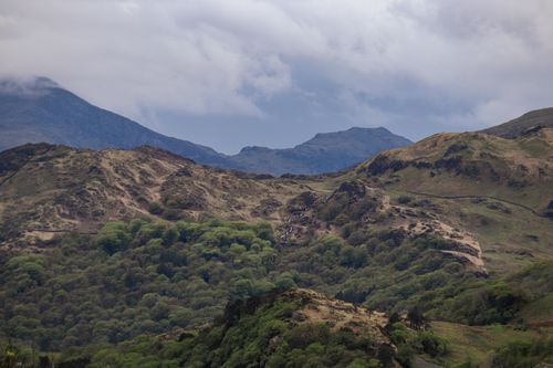 Free Aerial view of lush green hills and valleys in Wales under a cloudy sky. Stock Photo