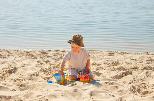 Free A young boy enjoying a sunny day at the beach, playing with toys in the sand. Stock Photo