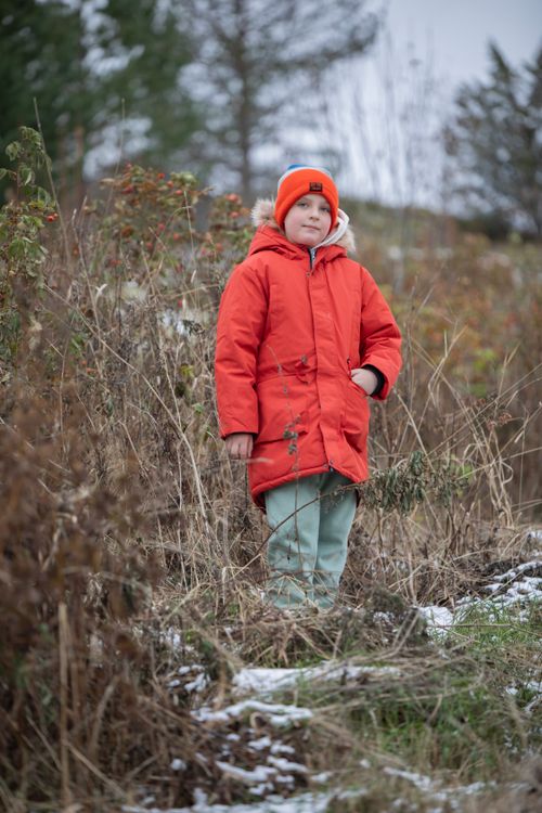 Free Child in a vibrant red jacket standing in a wintery outdoor rural setting. Stock Photo