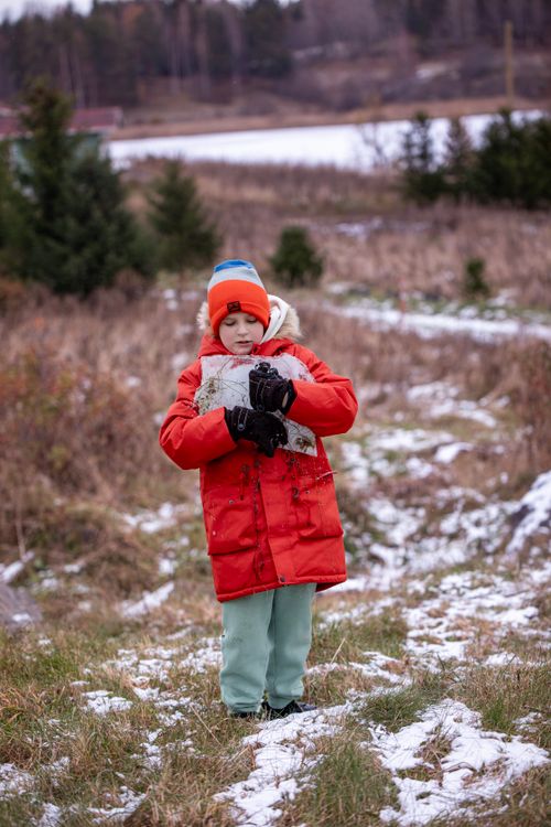 Free A young child in a red winter coat holding snow in a scenic outdoor setting. Stock Photo