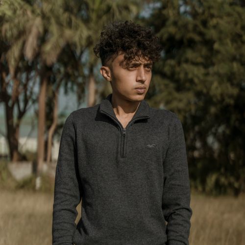 Free Stylish portrait of a young man with curly hair in a natural outdoor setting. Stock Photo