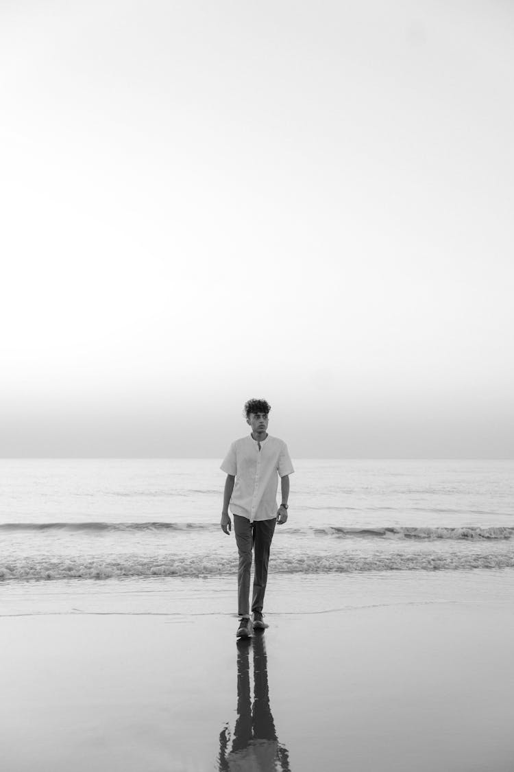 Young Man Walking On A Wet Beach