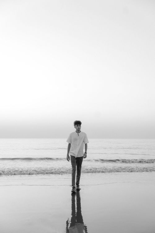Free Man walks peacefully on the beach with reflection in black and white. Stock Photo