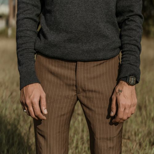 Free Man's fashion shoot outdoors featuring brown pinstripe pants and a gray sweater with accessory focus. Stock Photo