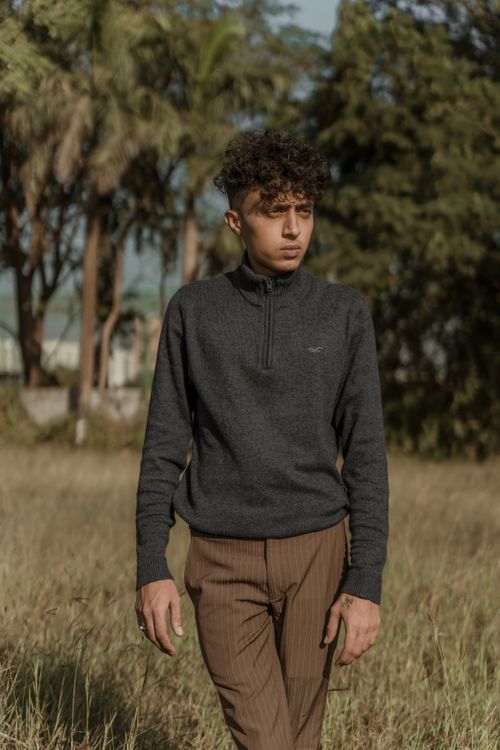 Free Man with curly hair and brown pants posing outdoors in autumn fashion. Stock Photo