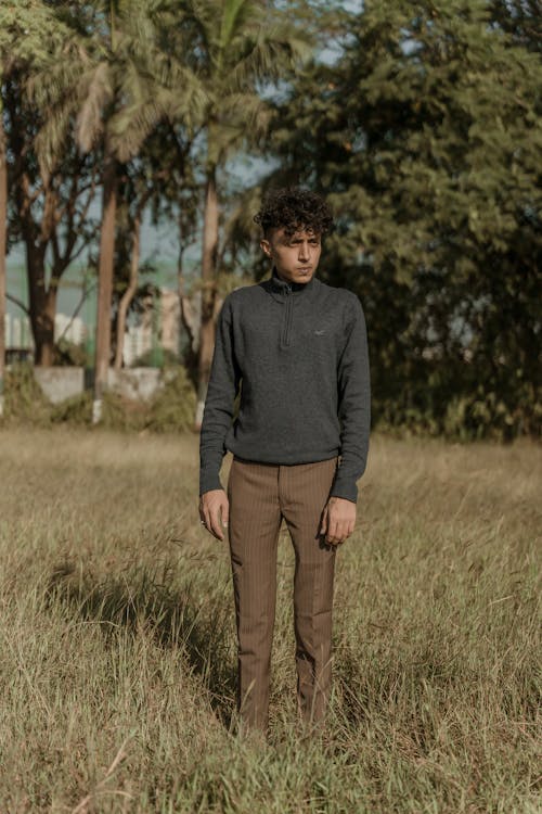 A man standing in a field wearing brown pants