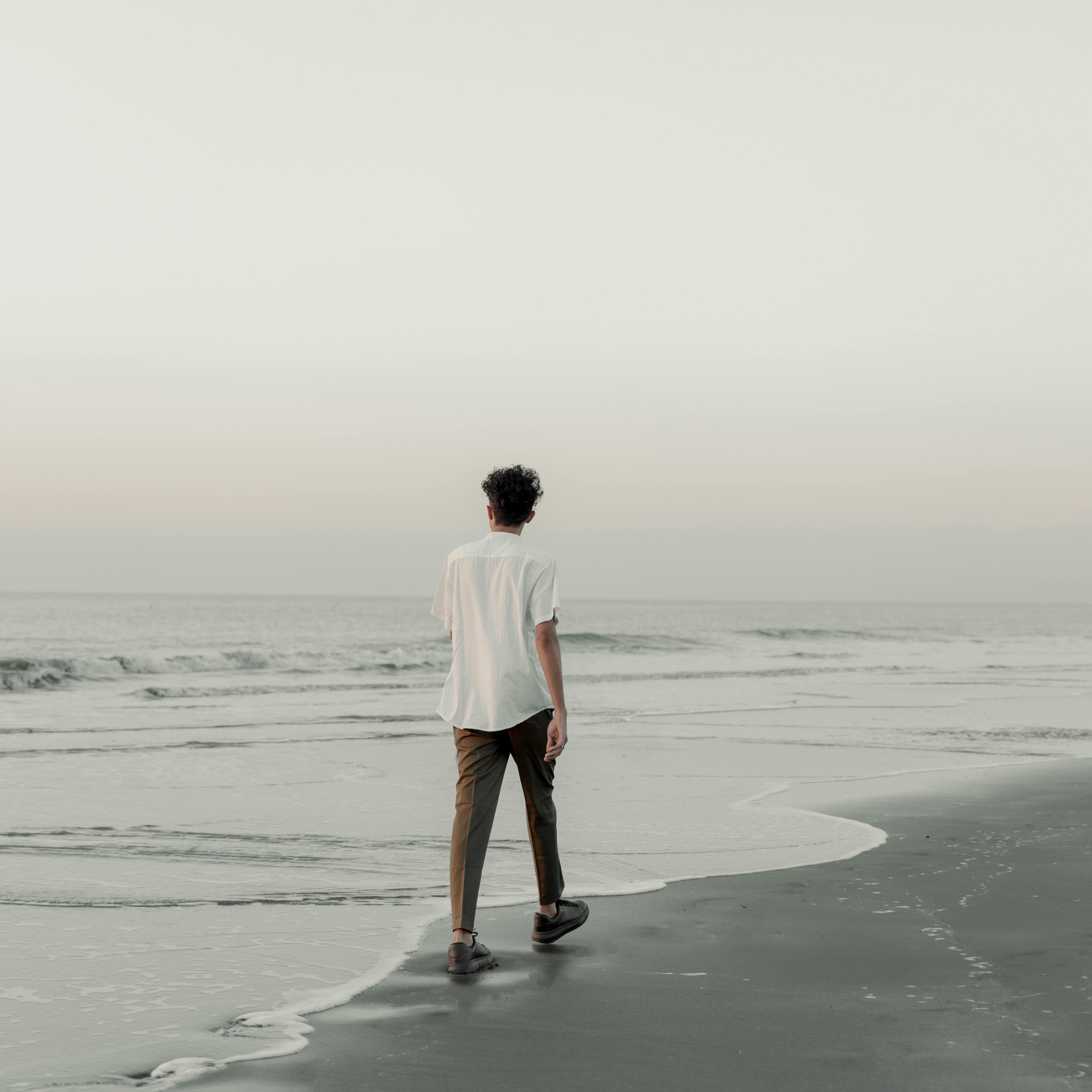 A person walks along the seashore during sunset, embracing tranquility and solitude.