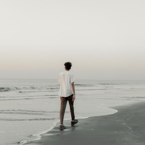 Free A person walks along the seashore during sunset, embracing tranquility and solitude. Stock Photo
