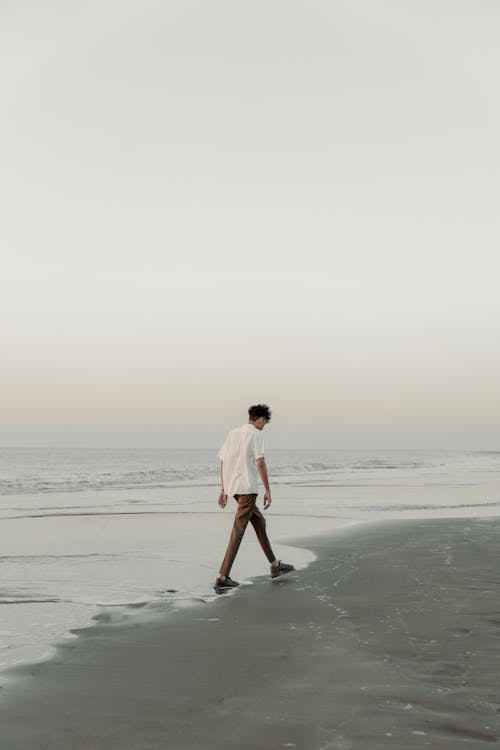 A man walking on the beach at sunset