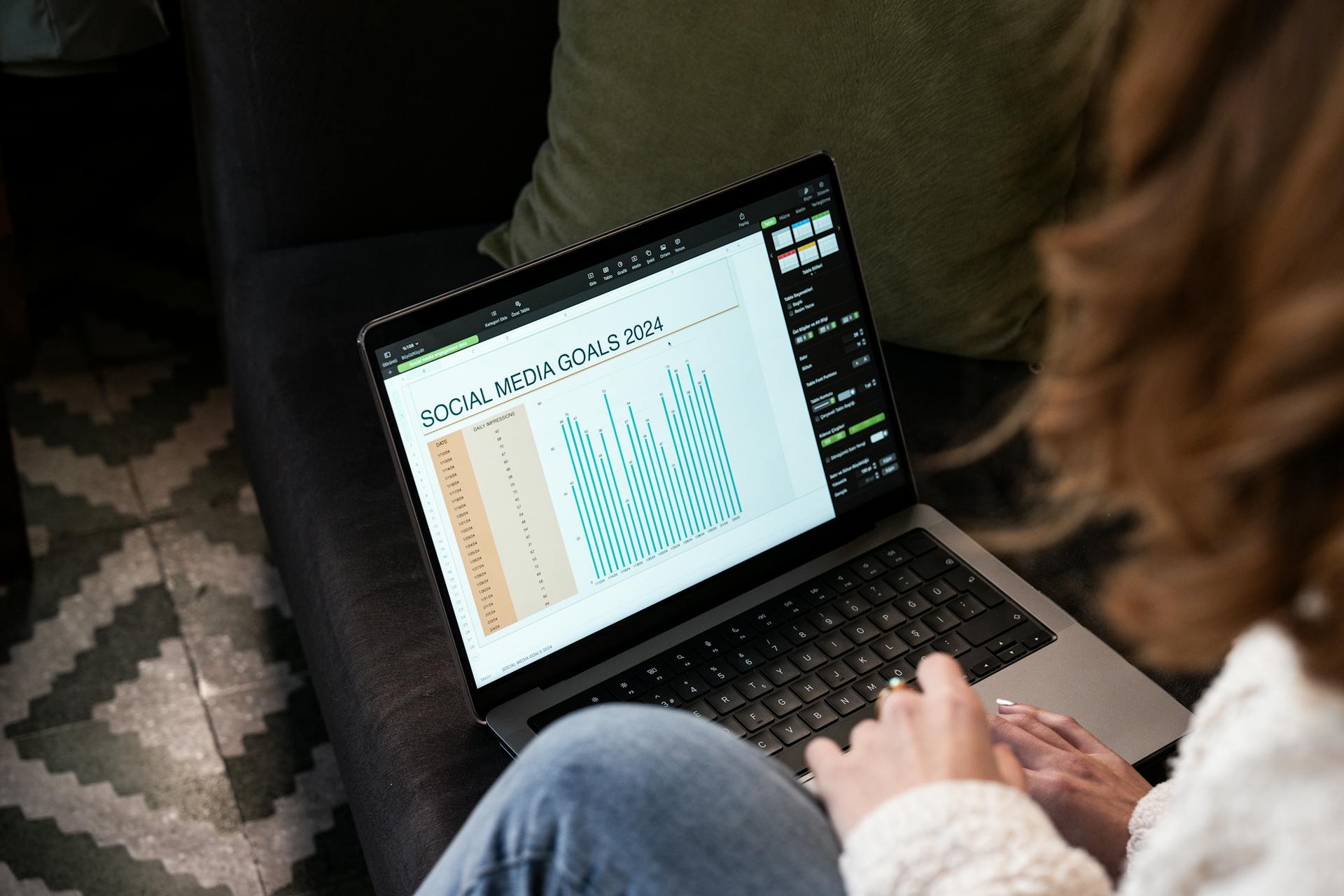 Woman Sitting on a Sofa with a Laptop Displaying a Chart