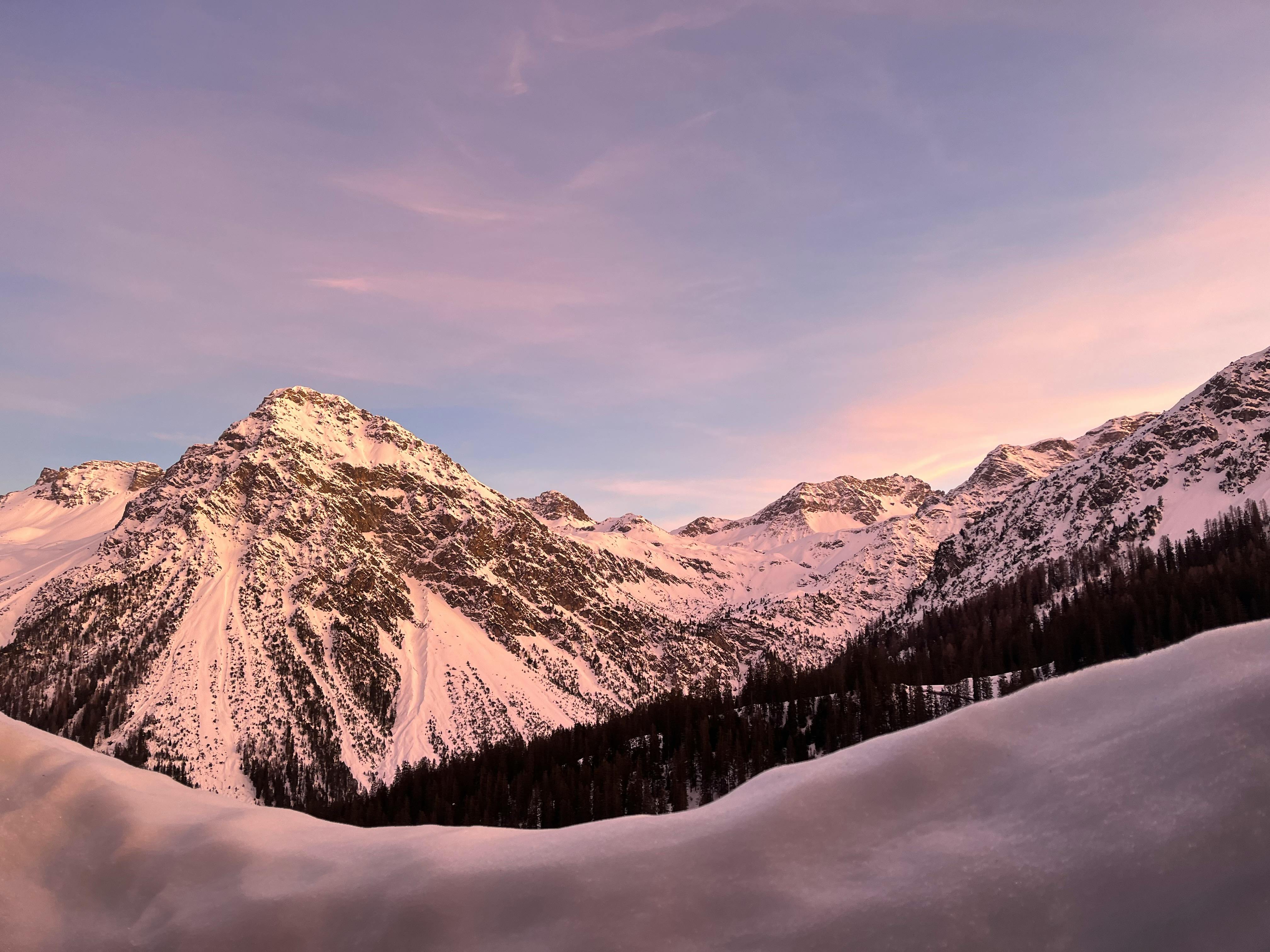Magnificent snowy Alps at sunrise in Arosa, Switzerland, showcasing serene winter beauty.